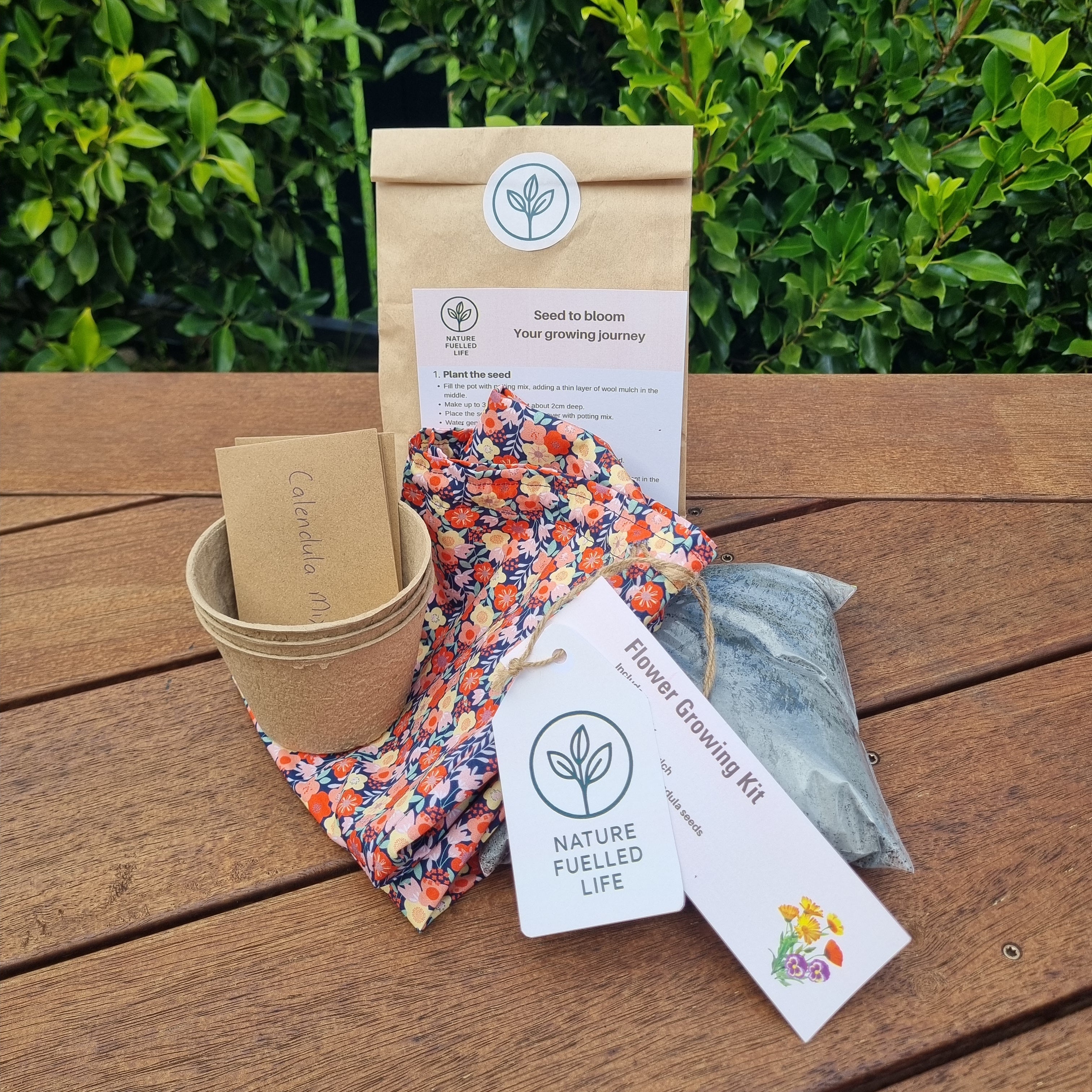 Flower growing kit with packaging on a wooden surface and greenery in the background
